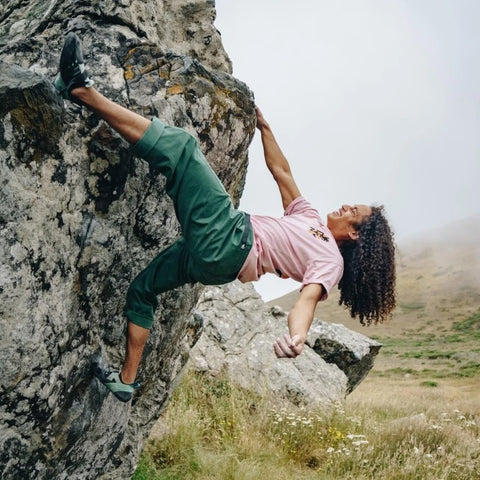 gramicci clothing action shot of a female climber on a rock leaning back with one arm free wearing Gramicci clothing products.
