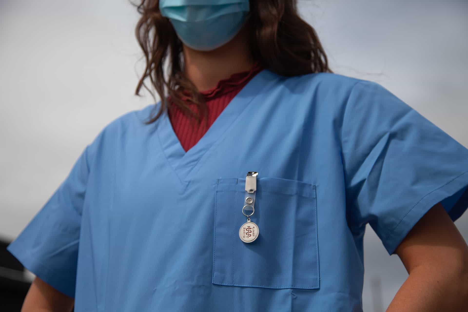 A female in blue scrubs with a front check pocket
