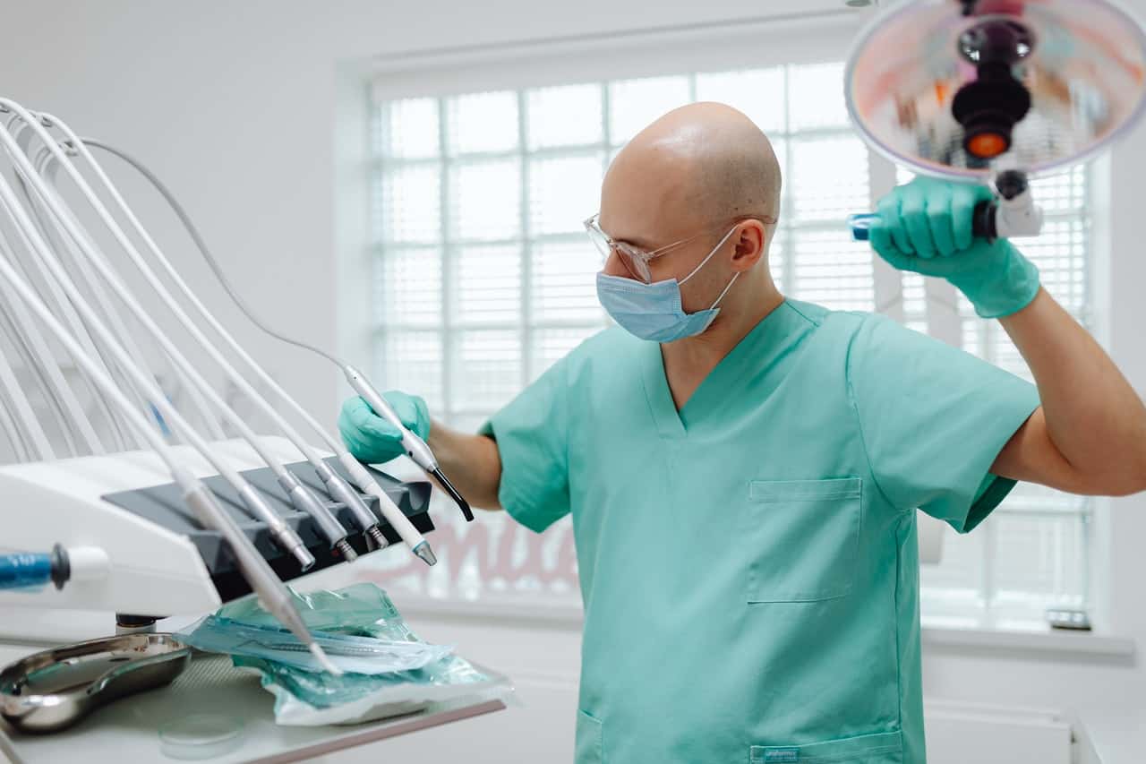 A male nurse in green scrubs looking through medical tools. 