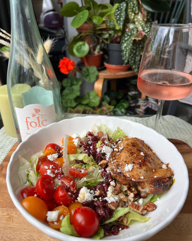 A chicken, walnut and cranberry salad in a white bowl. Accompanied by a bottle of folc English rosé and a glass of rosé