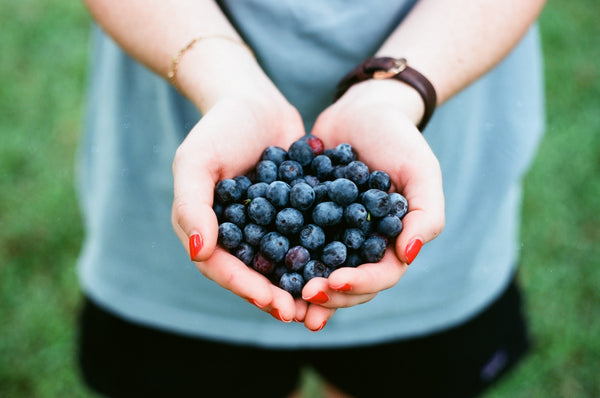 woman with red nails holding out blueberries on her palms