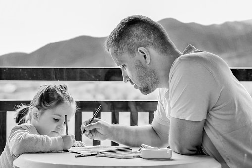 black and white photo of dad teaching daughter to wrote