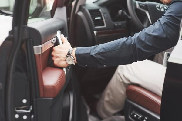 man wearing watch about to close car door