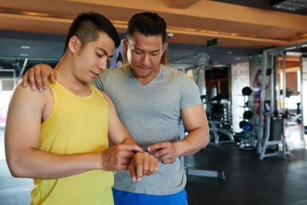 two men checking out fitbit watch inside a gym