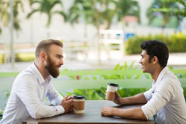 two men talking while drinking coffee