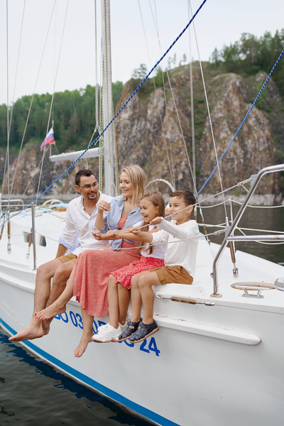 young family of four laughing while sitting on yacht 