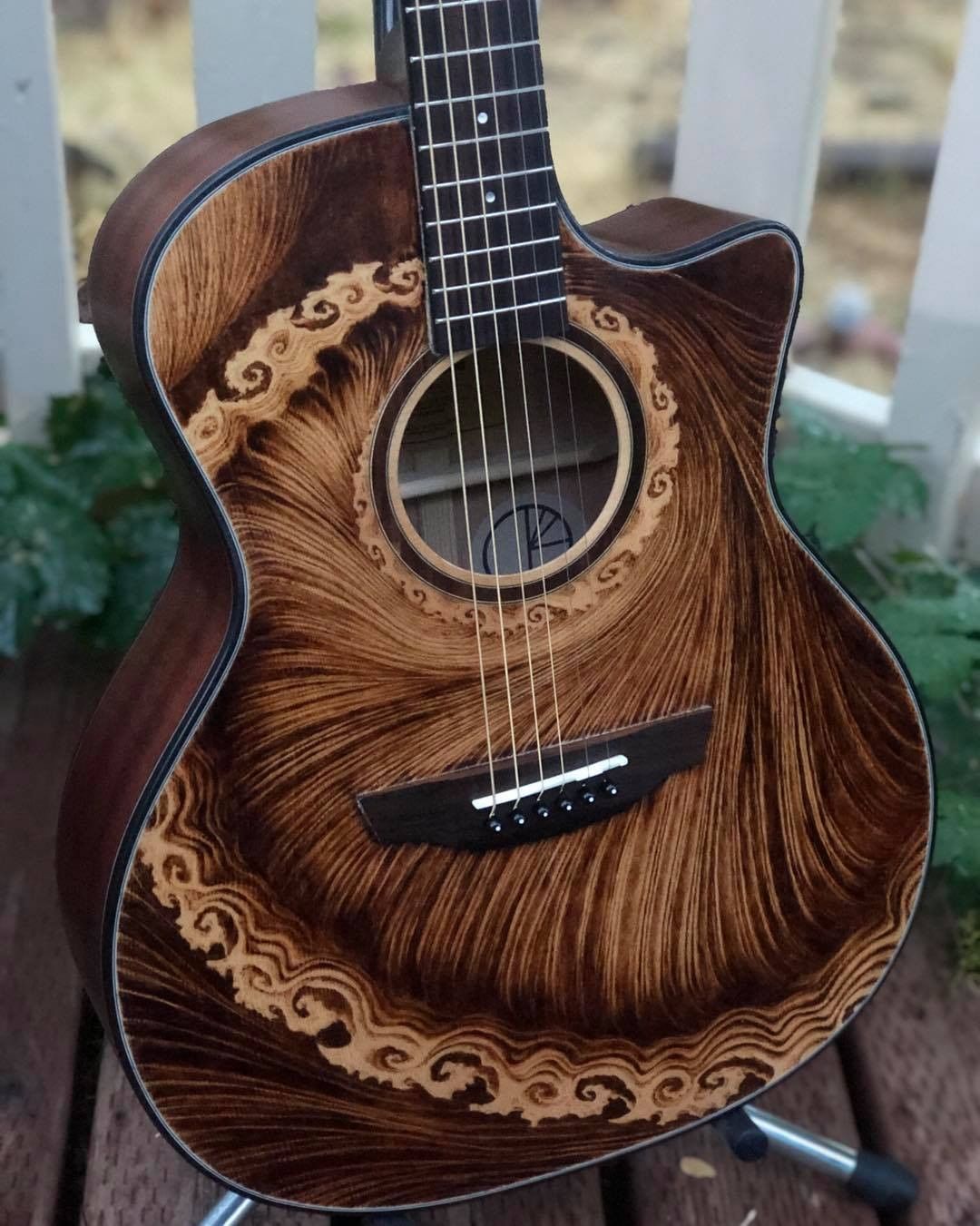 An Orangewood Morgan Mahogany acoustic with a custom wood burned top, featuring swirly abstract designs.