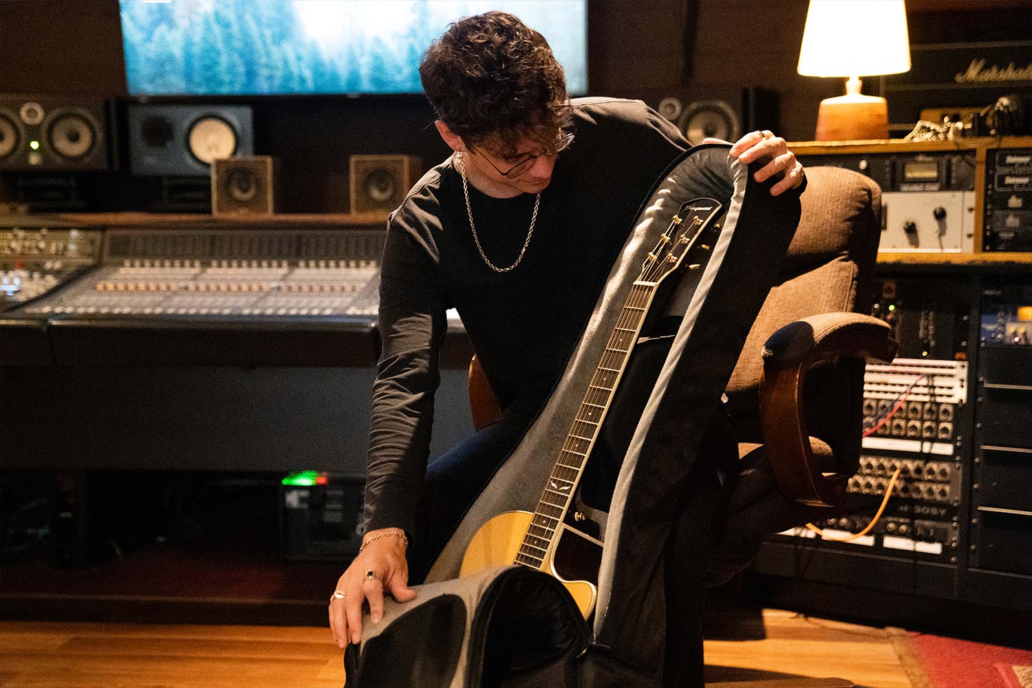 Person unzipping a guitar case revealing an acoustic guitar