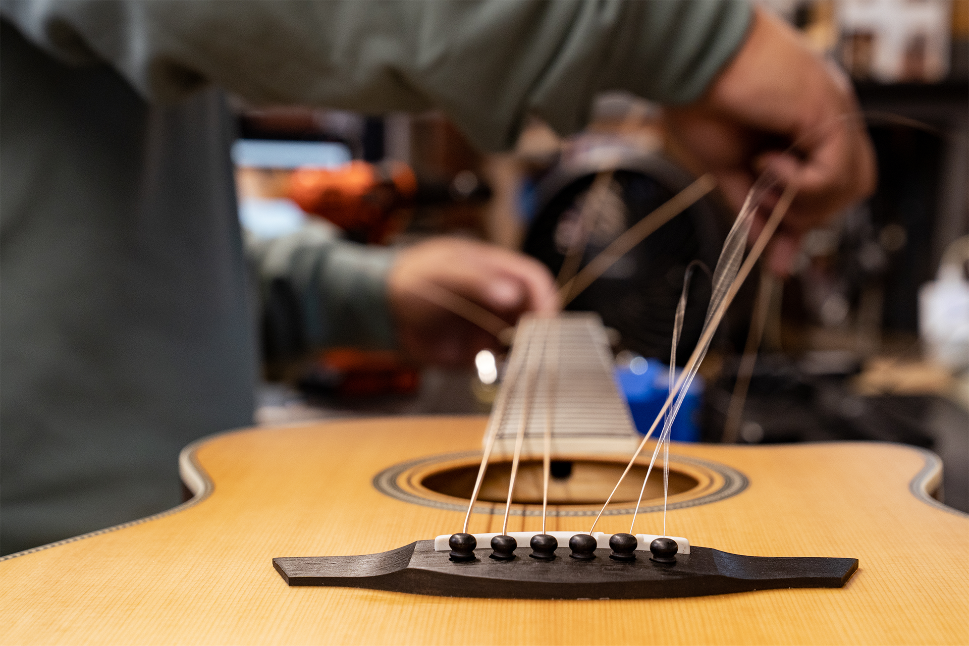 A close-up on the bridge of a guitar in the middle of a restring.