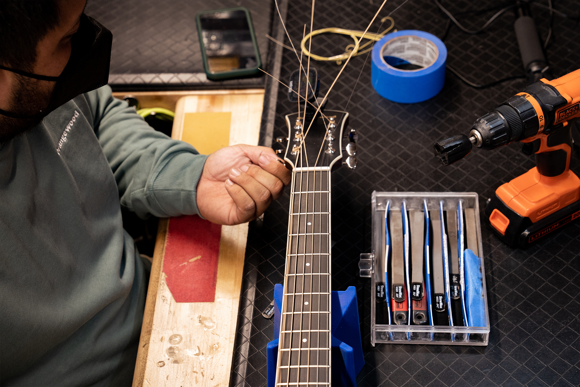 A guitar on the technician's bench getting a tune-up.