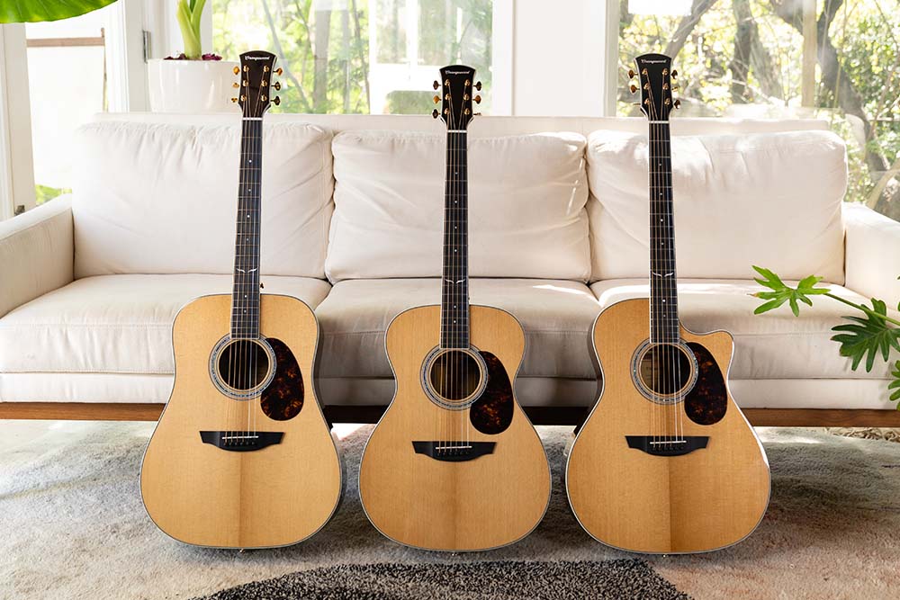 Three guitars with tortoise pickguards leaning on a white sofa