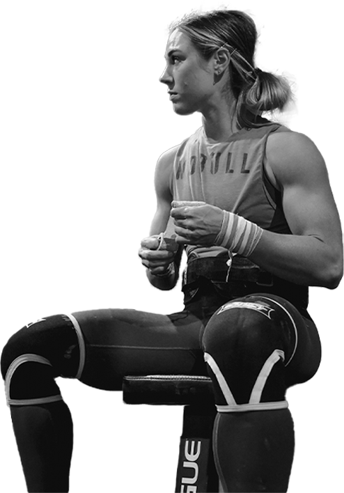 Black and white photo of Brooke Wells sitting on a rowing machine drinking podium hydro salt