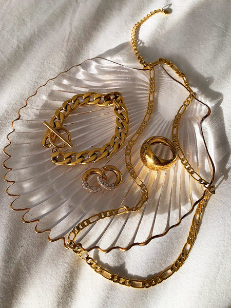 gold bracelet, rings and earrings on white linen