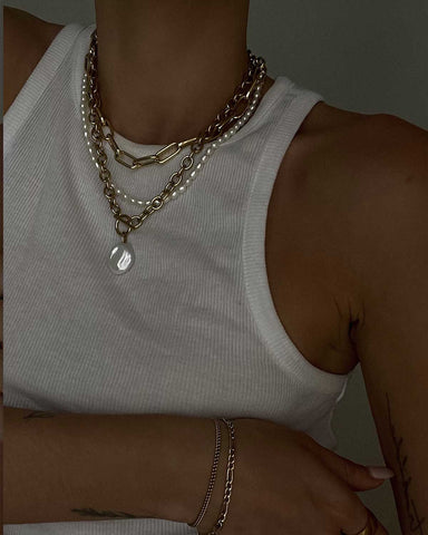 model wears a pearl layered necklace set with a white tank top