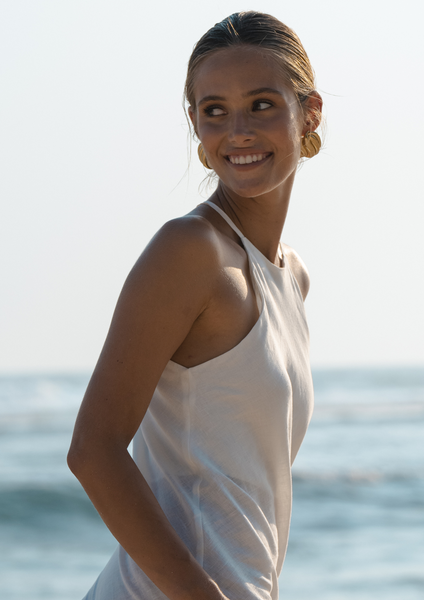 styling chunky gold earrings and white dress at the beach