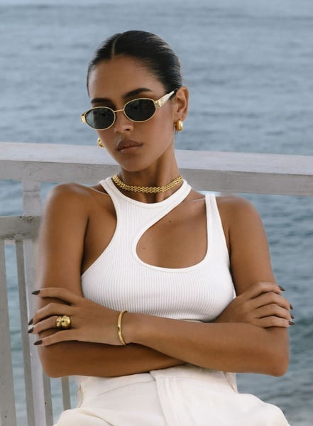 model wearing a gold jewelry set with a white top