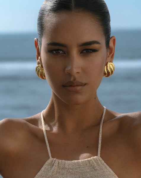 chunky gold earrings on a model in a summer dress