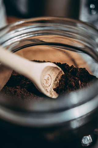 used coffee grounds in a jar with a wooden spoon