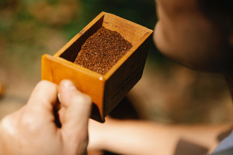 man holding wooden container filled with coffee grounds