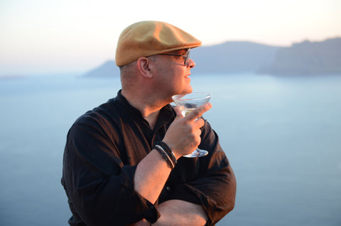 Michael Perris, co-founder of the niche fragrance brand The Bubble Collection, enjoying a cocktail while taking in the famous Santorini sunset overlooking the caldera at Perivolas Hotel in Oia.