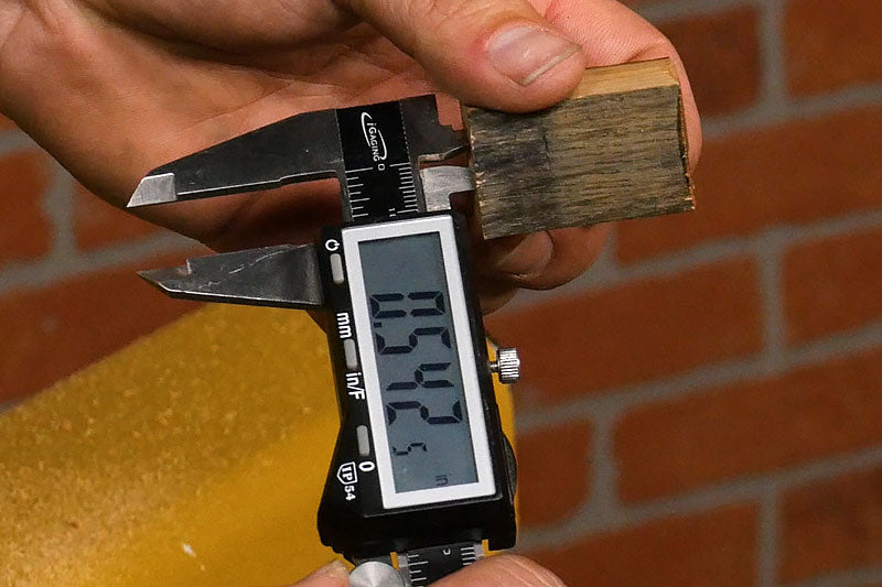 Using calipers to measure the inside diameter of the brass tube.