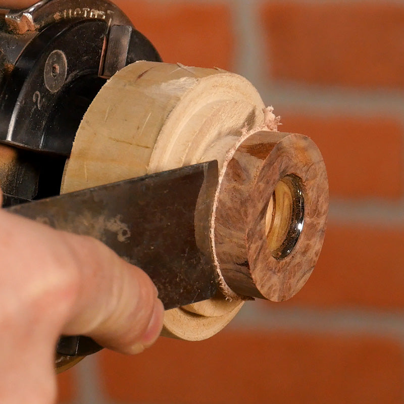 Using a putty knife to pry the blank off the waste block.