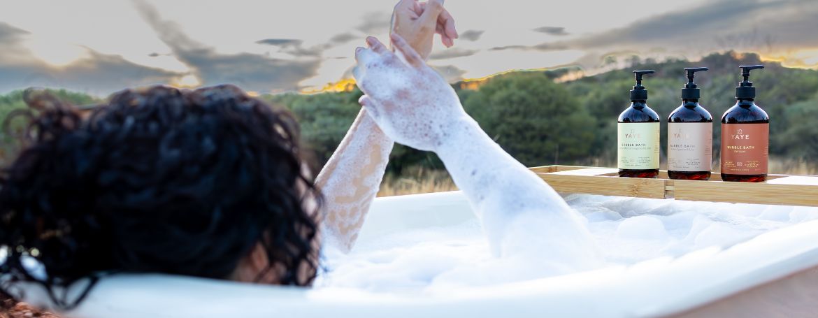 woman soaking in a bath filled with Yaye’s foamy bubbles, enjoying a skin-friendly formula designed for hydration and comfort