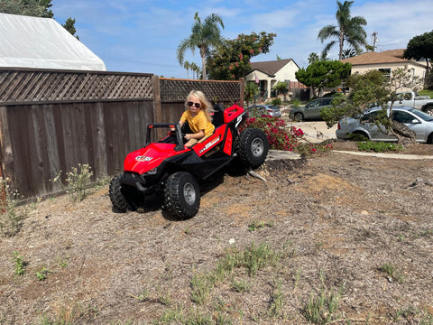 a kid playing around with his red 24 Volts All Wheel Drive Buggy Power Wheels
