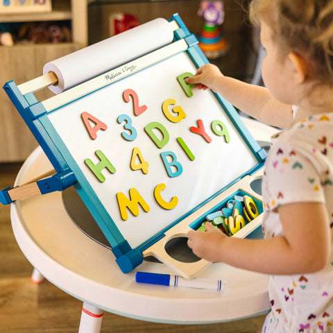 Girl playing with magnetic letters on Melissa & Doug Tabletop Easel