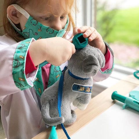 Girl playing with Melissa & Doug Doctor Role Play Costume Set and examining her stuffed animal