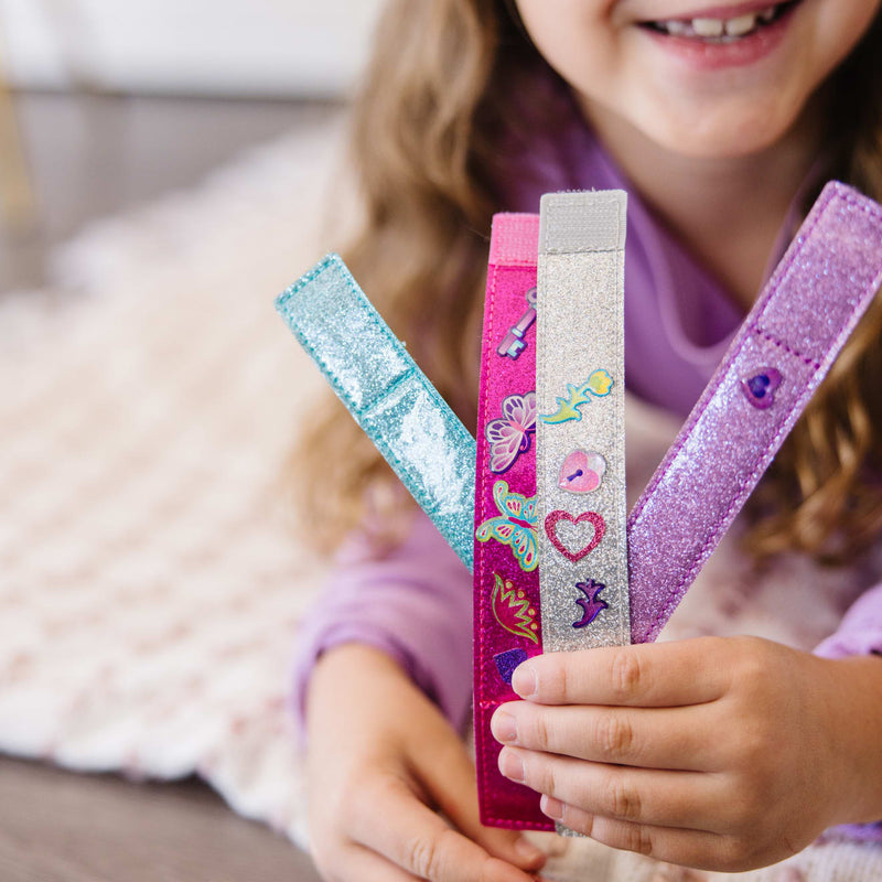 A kid playing with the Melissa & Doug Design-Your-Own Bracelets With 100+ Sparkle Gem and Glitter Stickers