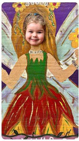 A smiling Abby posing behind a painted photo wall with face-cutout, so she looks like a fairy queen