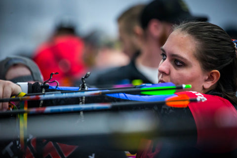 An archer pulls her arrows out from the target.