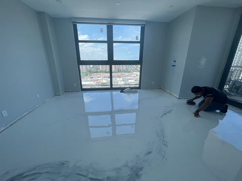 contractor polishing gray and white epoxy floor inside apartment