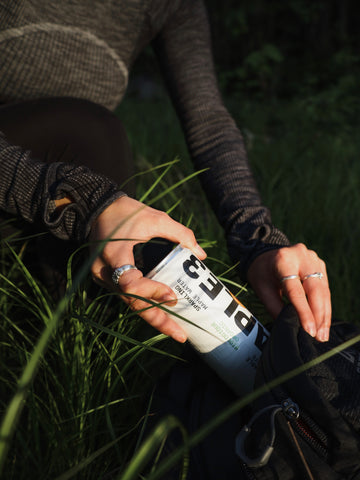 Girl putting her sparkling Maple 3 water in her backpack during a hike.