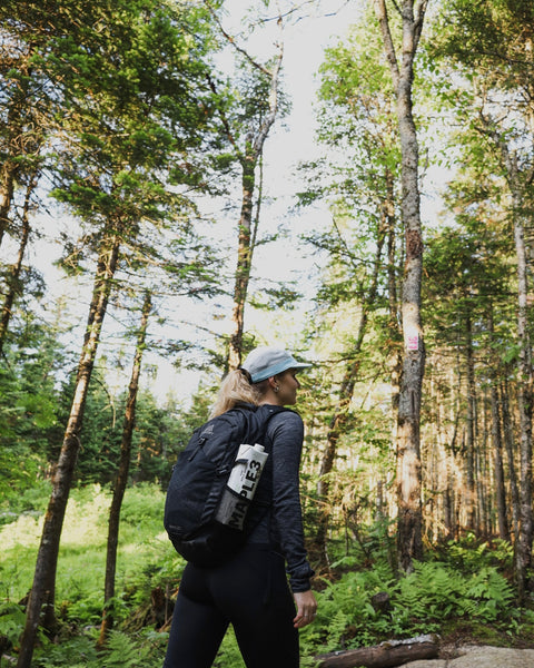 Girl hiking in the woods with her plant-based Maple 3 water in her backpack.