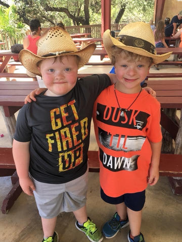 Two young boys in cowboy hats with interlinked arms
