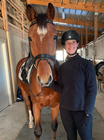 Amy Cairy and her dressage horse Liam standing in a barn aisle