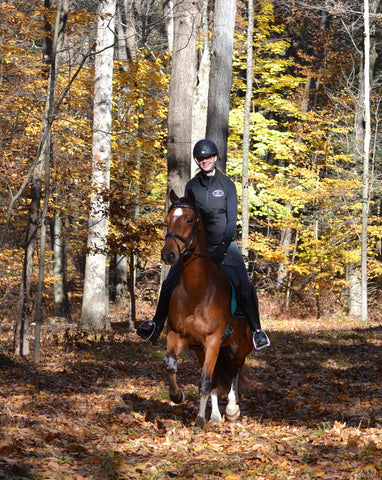 Amy Cairy riding  her horse Liam in the woods