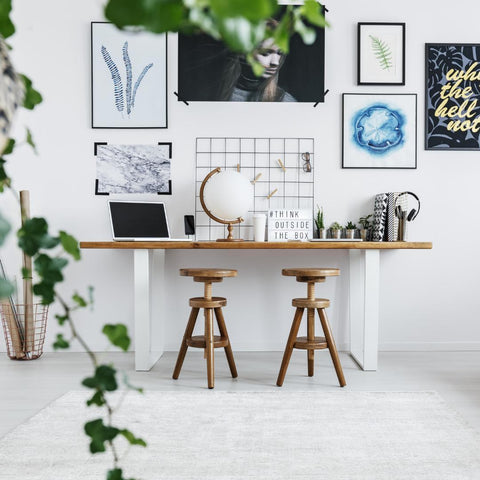 A modern workspace with a desk, two stools, a computer, and decorations