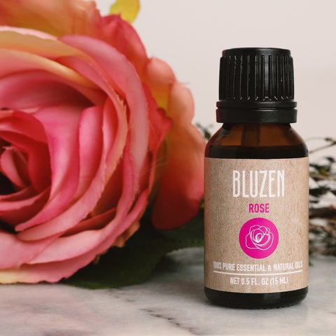 A Bluzen Rose Essential Oil next to a rose