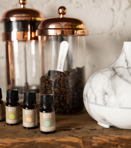 BluZen essential oils on a table with a diffuser and a can of coffee beans