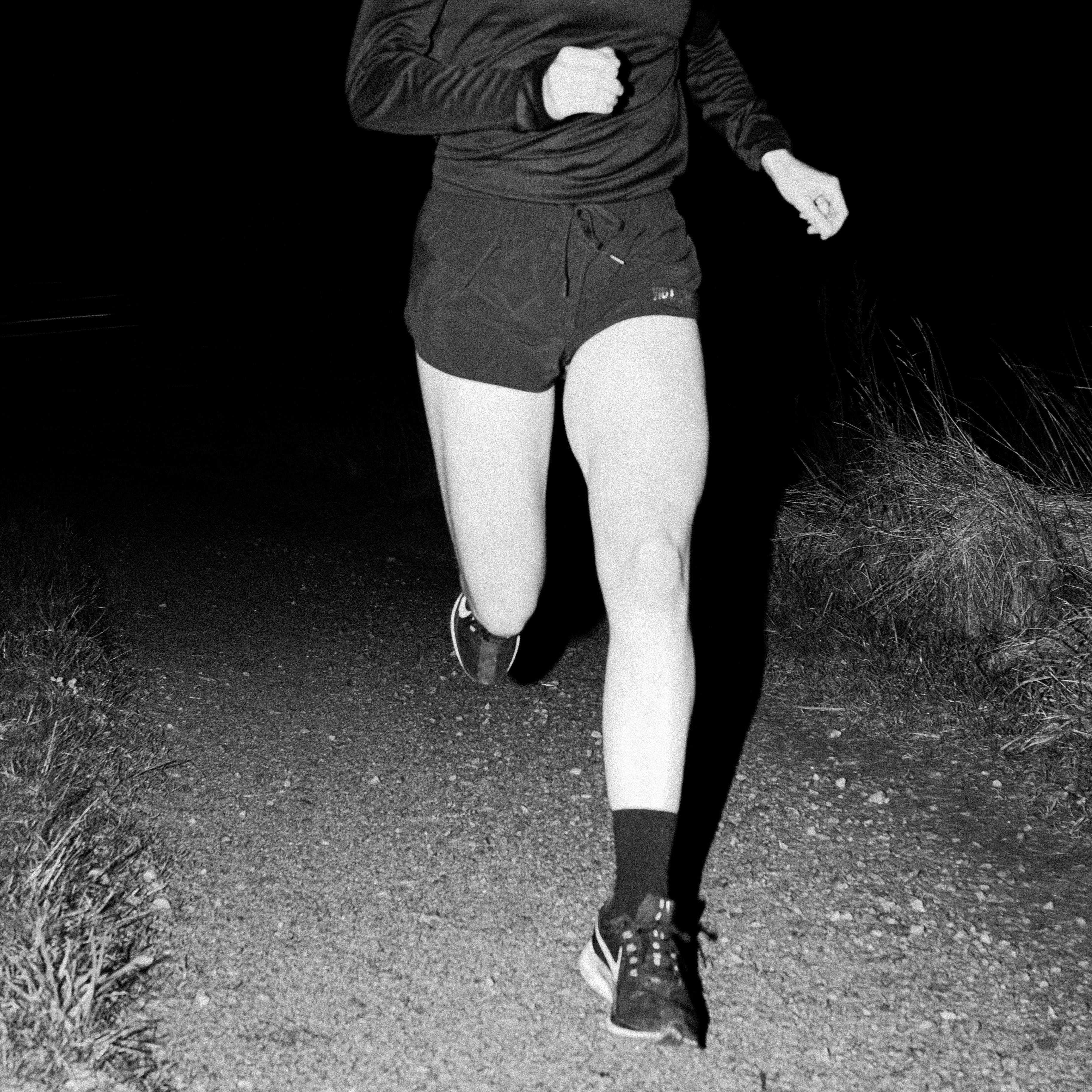 black and white image of runner running down a track