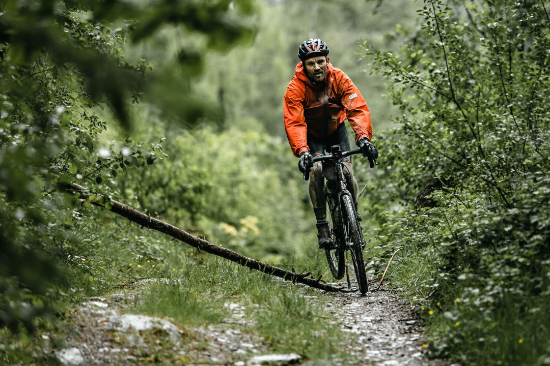 cyclist in an orange coat cycling in the woods
