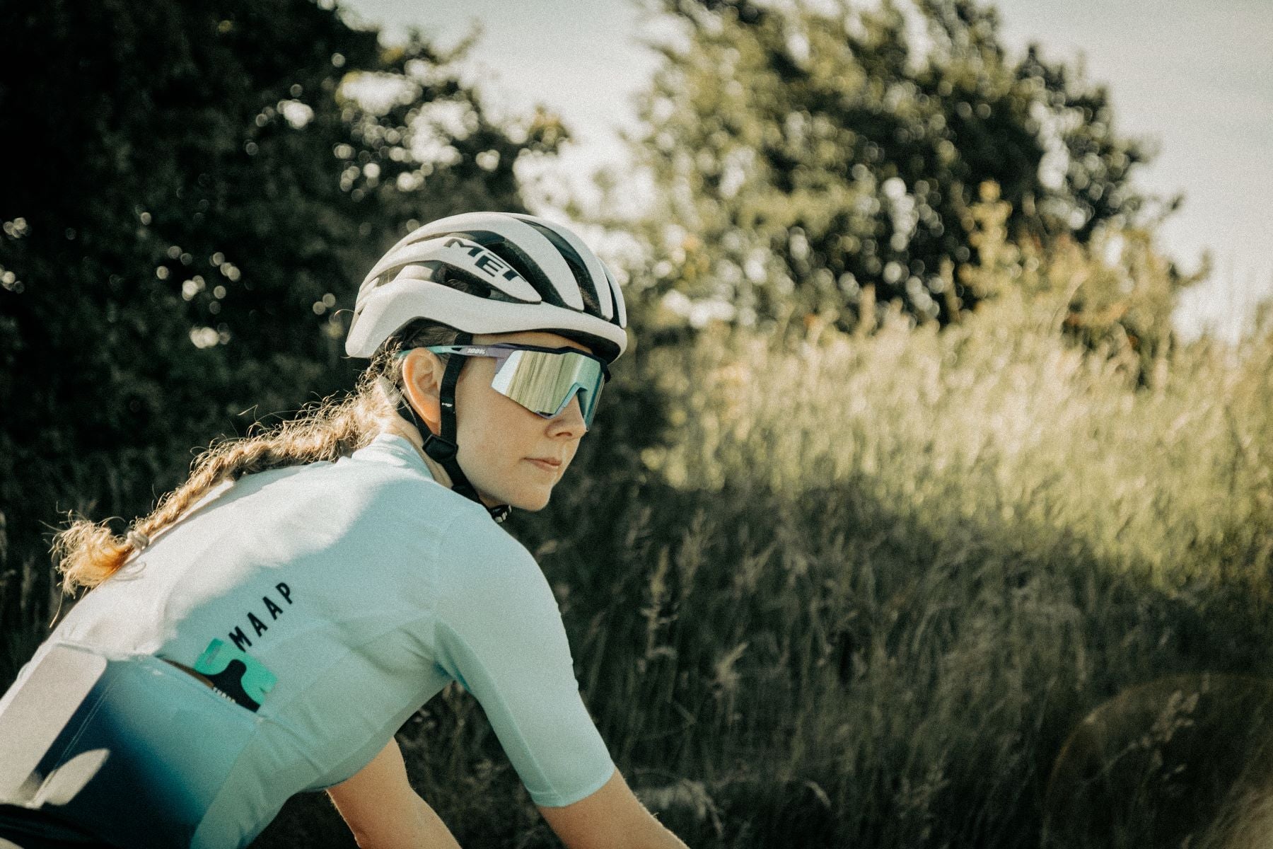female athlete wearing helmet on a bike cycling through country lanes