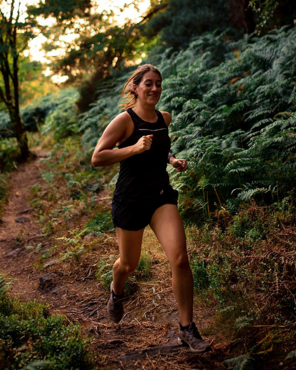 female athlete running through the woods