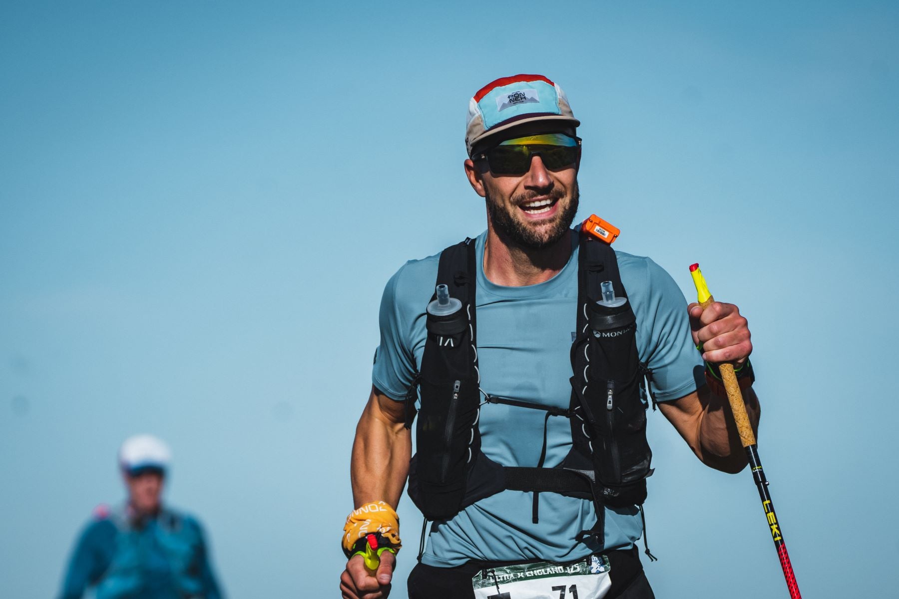 smiling athlete training on the hills with vest for water bottles