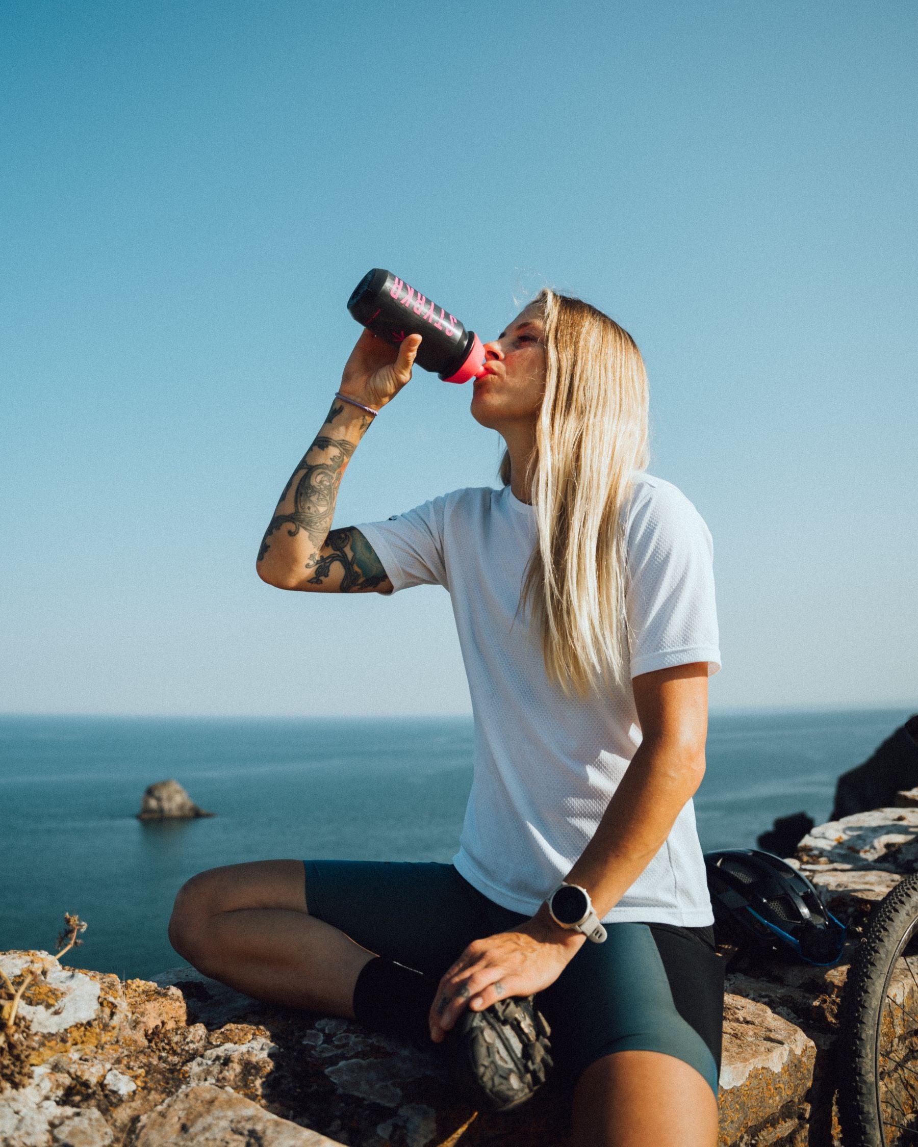 Ciclista femenina de Styrkr rehidratándose con una botella de agua de Styrkr