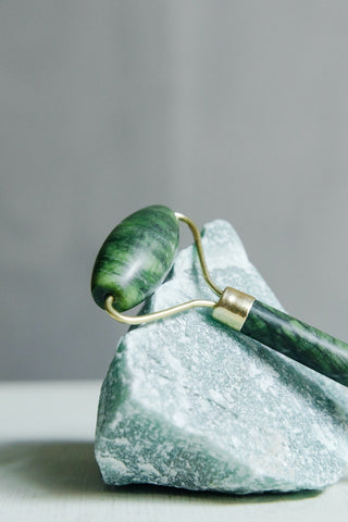 A high quality jade roller resting against a jade stone