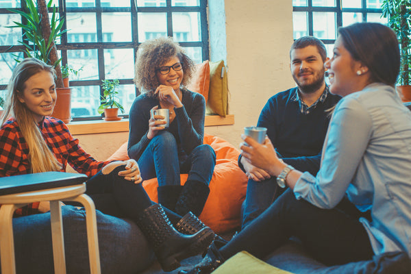 4 individuals in informal conversation seated on beanbags